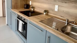 Een moderne keuken met lichtblauwe kastjes, een houten aanrecht en roestvrijstalen apparatuur, inclusief een inbouwoven.