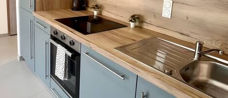 Eine moderne Küche mit hellblauen Schränken, einer Holzarbeitsplatte, Edelstahlgeräten und einem eingebauten Backofen.