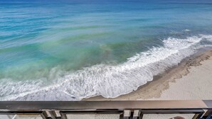 A beach view with clear water and a sandy shore.