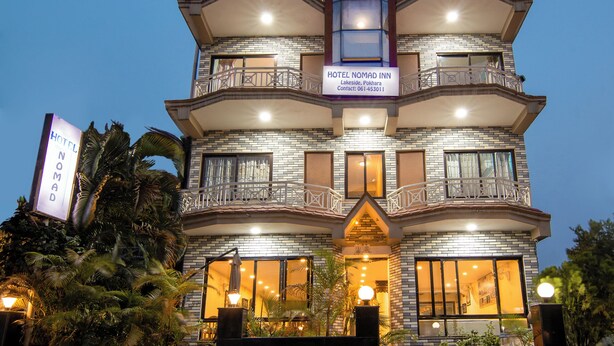A multi-story hotel with balconies and a sign indicating it is a 'Hotel Nomad Inn'. - Hotel Nomad Inn (Pokhara)