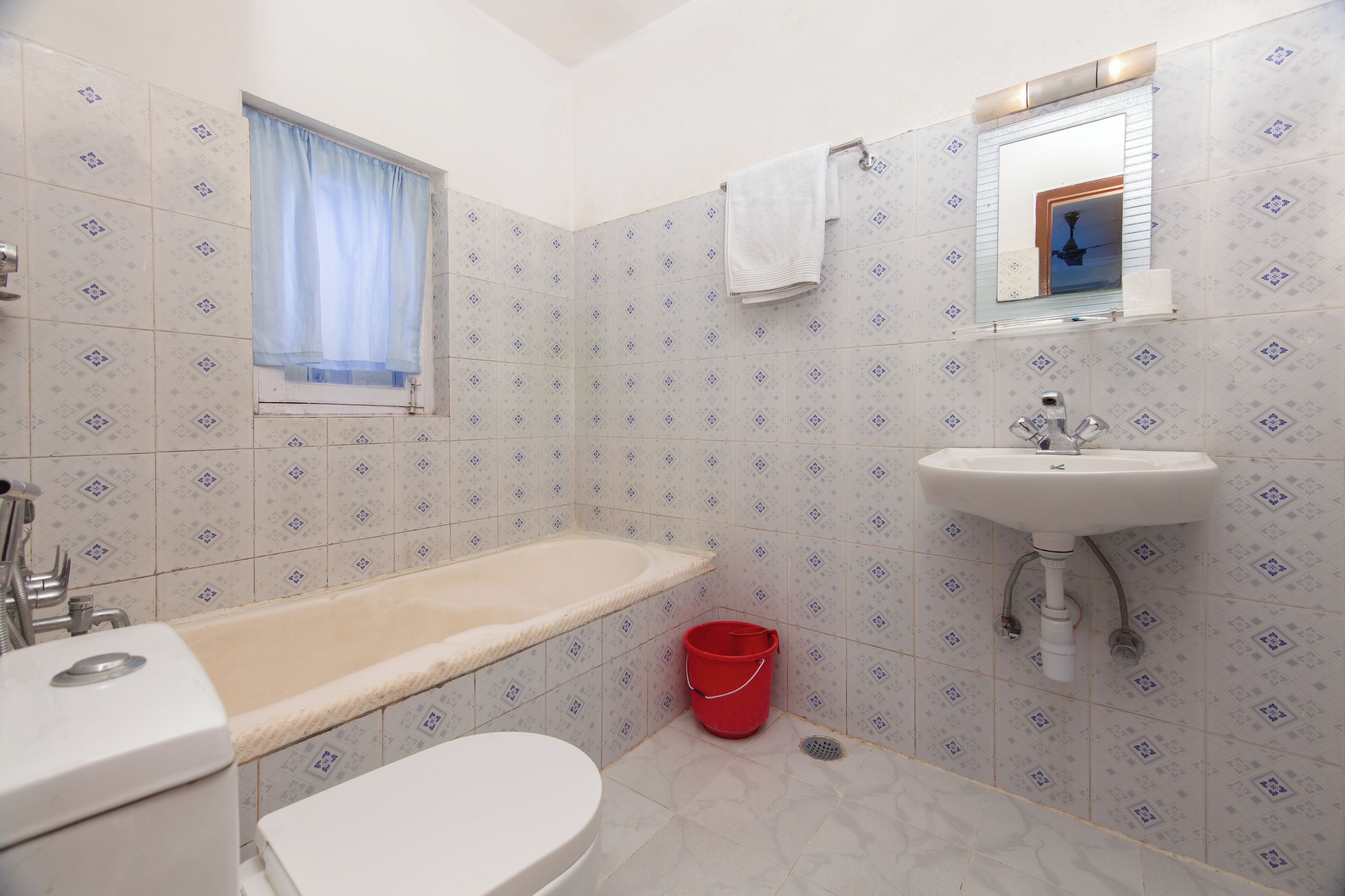 Ein Badezimmer mit Badewanne, Toilette, Waschbecken und einem roten Eimer.