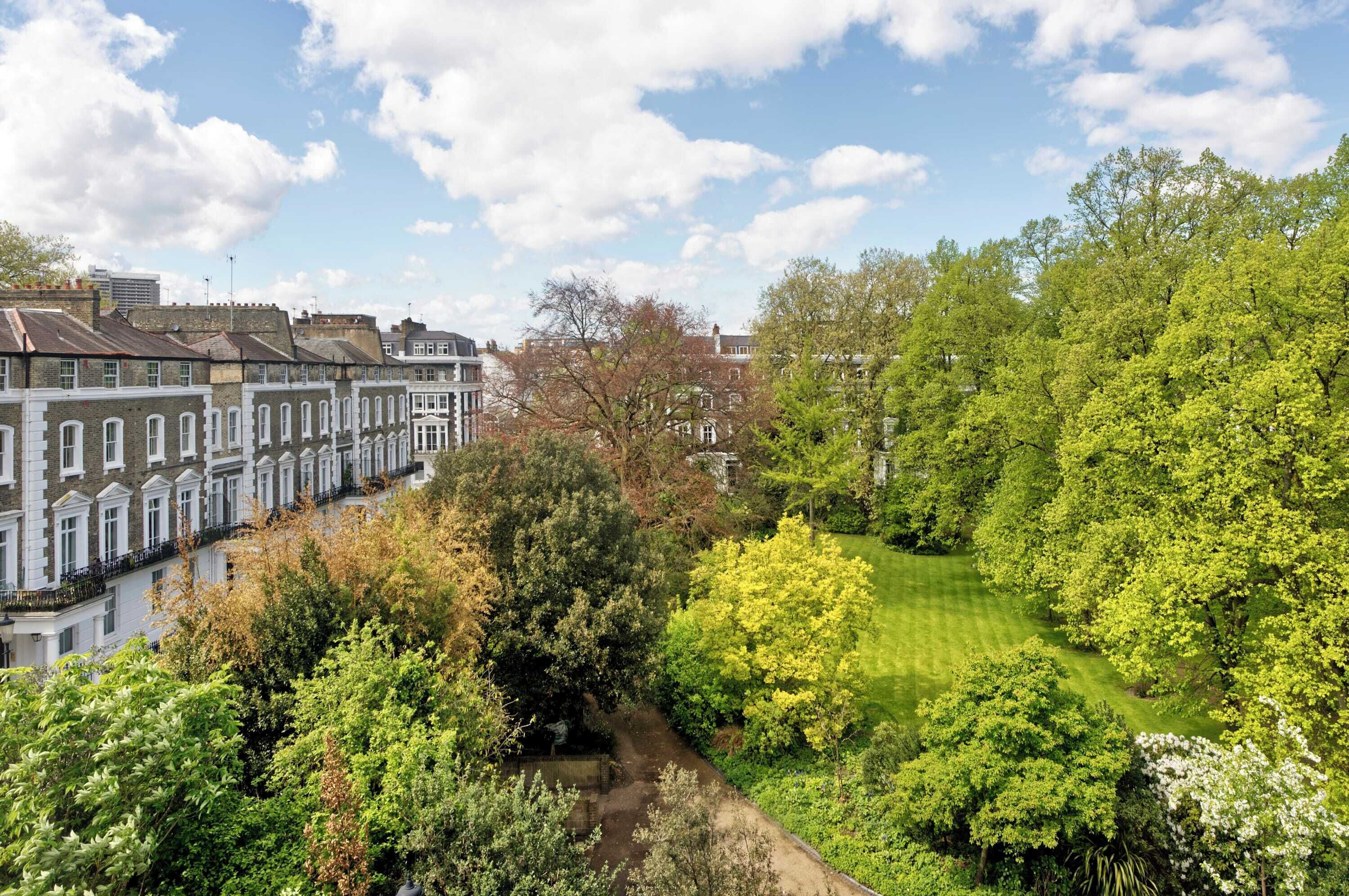A residential area with terraced houses, a well-maintained lawn, and mature trees.