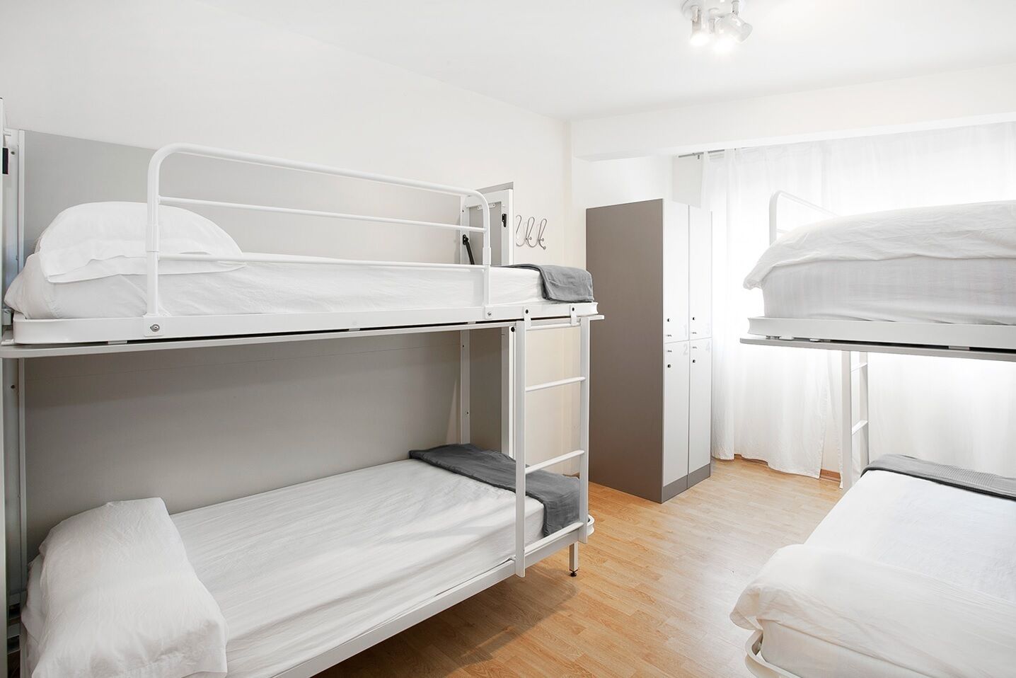 A dormitory room with bunk beds, a wardrobe, and a small desk.