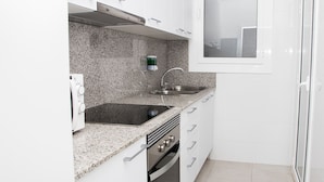 A compact kitchen with white cabinets, a granite countertop, a stainless steel sink, and a built-in oven. - Sant Jordi Apartments Sagrada Familia (Barcelona)