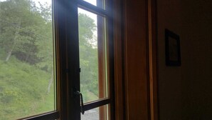 A room with a large window, wooden door, and a framed picture on the wall.
