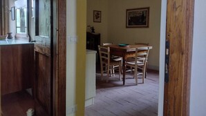 A wooden dining area with a table and chairs, a light fixture above, and a painting on the wall.