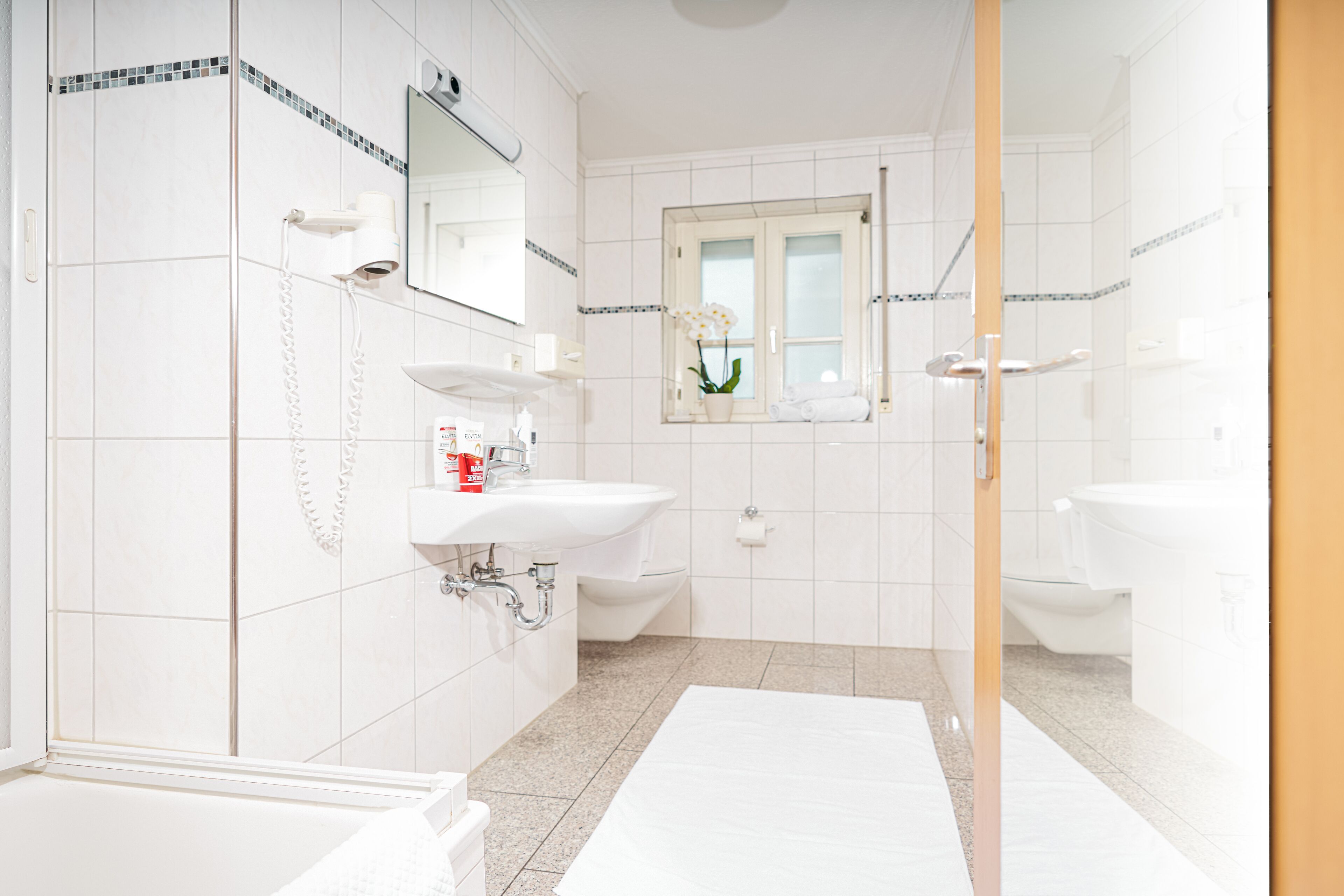 A modern bathroom with two sinks, a shower, and a toilet.