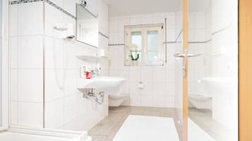A modern bathroom with two sinks, a shower, and a toilet.