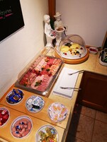 A buffet table with various food items including meats, cheeses, and pastries.