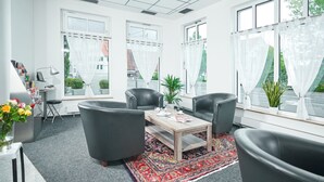 A modern office space with leather chairs, a wooden table, and large windows with white curtains. - Apart Business Hotel  (Stuttgart)