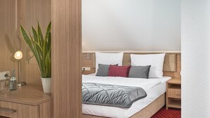 A hotel room with a bed, bedside tables, a lamp, and a potted plant. - Apart Business Hotel  (Stuttgart)
