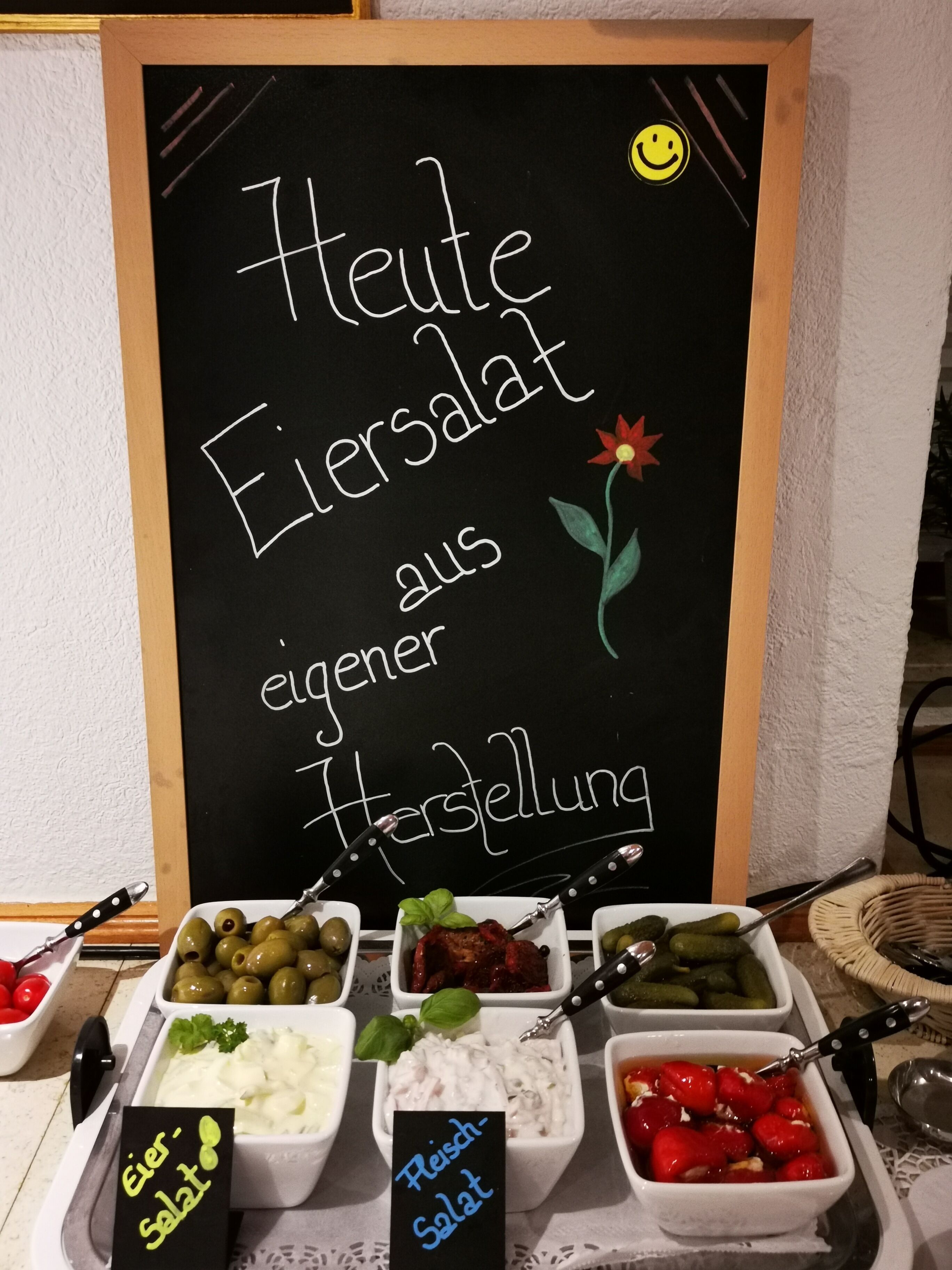 Eine Kreidetafel mit verschiedenen Gerichten und einem Smiley.