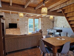 Un interior acogedor de madera con sofá, mesa de comedor y mesa de futbolín.