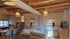 A cozy living area with a sofa, chairs, and a dining table. There is a kitchen area with a microwave and a TV.