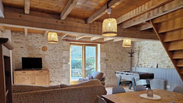 A cozy wooden interior with a sofa, dining table, and a foosball table.