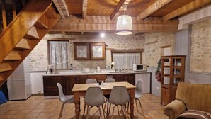 A cozy kitchen with a wooden staircase, a dining table with chairs, and a kitchen island with appliances.