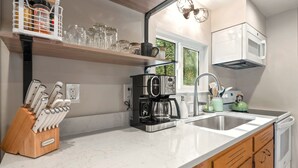 A modern kitchen with a marble countertop, a coffee machine, a kettle, and a knife block.
