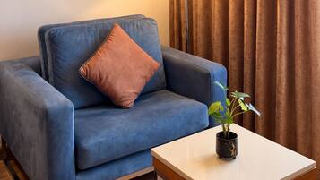 A room with a blue sofa, a lamp, a small table, and a plant.
