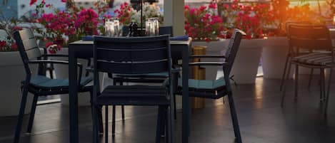 A terrace with a table and chairs, surrounded by potted plants and flowers.