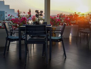 A terrace with a table and chairs, surrounded by potted plants and flowers. - Golden Tulip Muscat (Muscat)