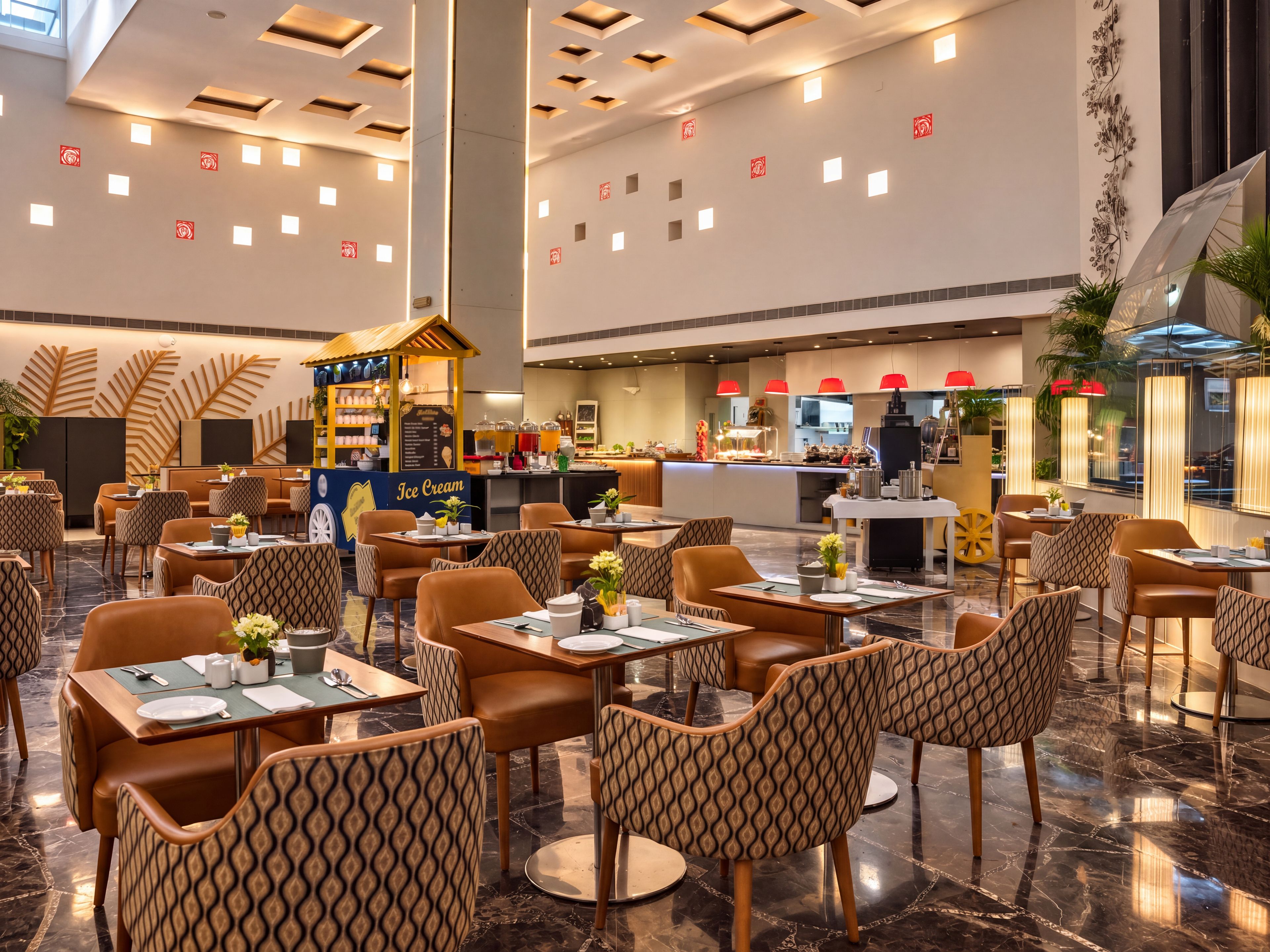 Een ruim restaurant met meerdere eettafels en stoelen, een centraal ijskraampje en een keuken op de achtergrond.