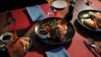 A dining table set with plates of food, a glass of orange juice, and a martini glass.