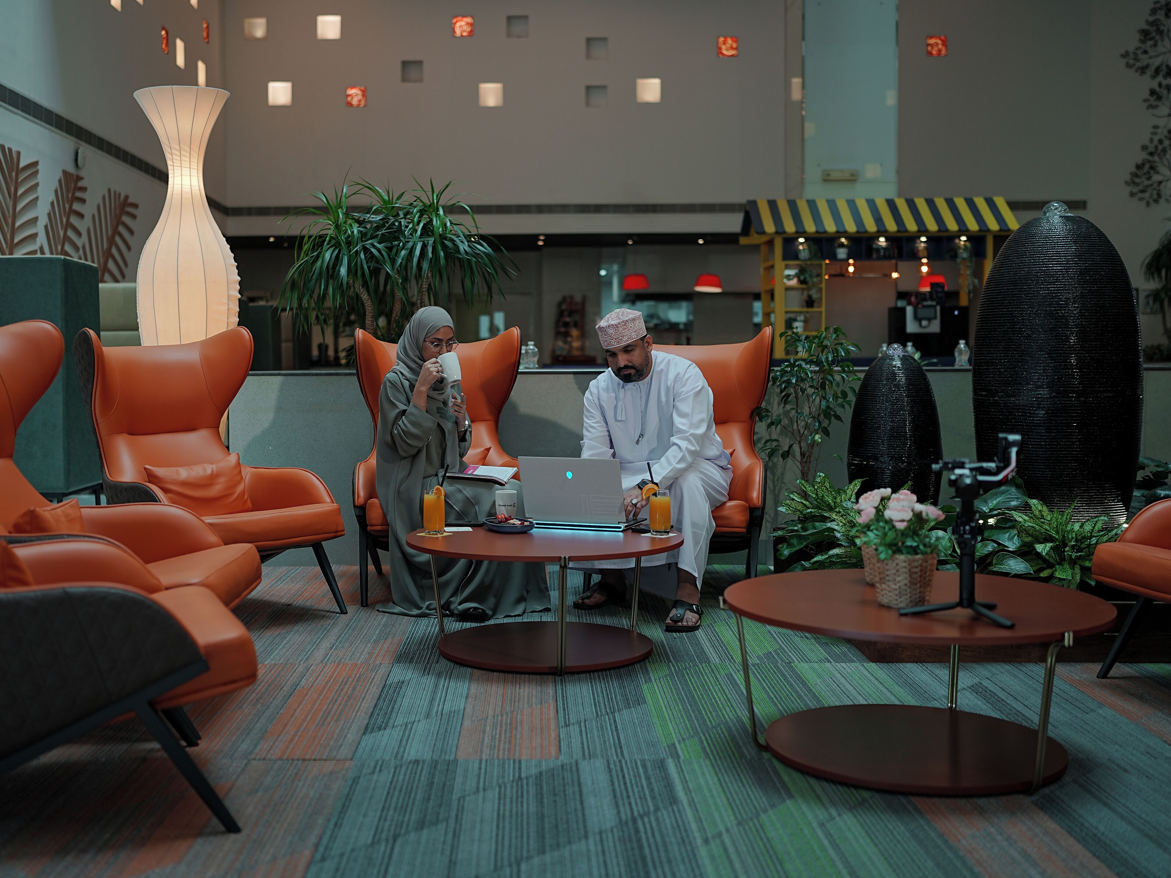 A modern lounge area with leather chairs, a round table, and a laptop.