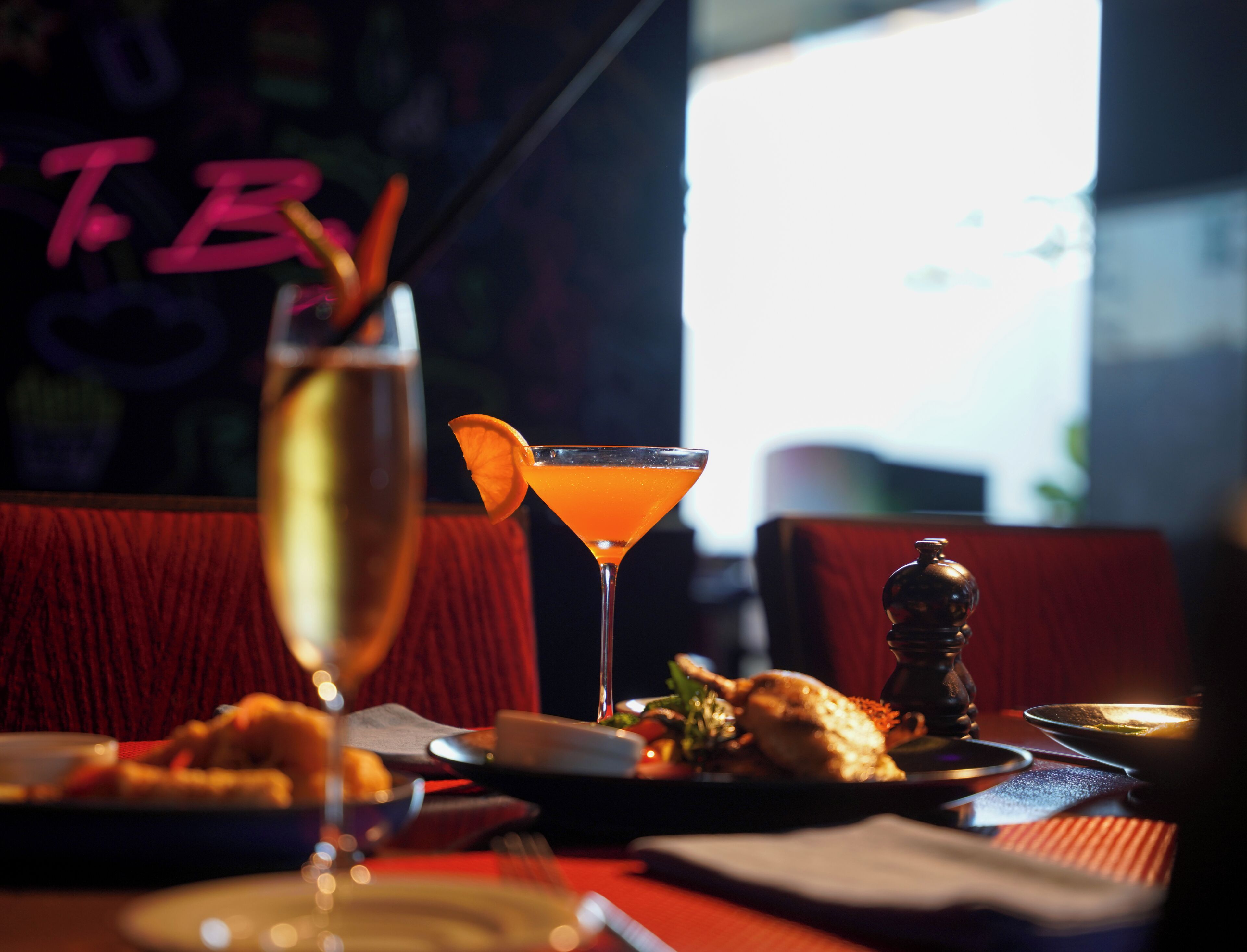 A restaurant setting with a cocktail glass, a bottle, and a plate of food.