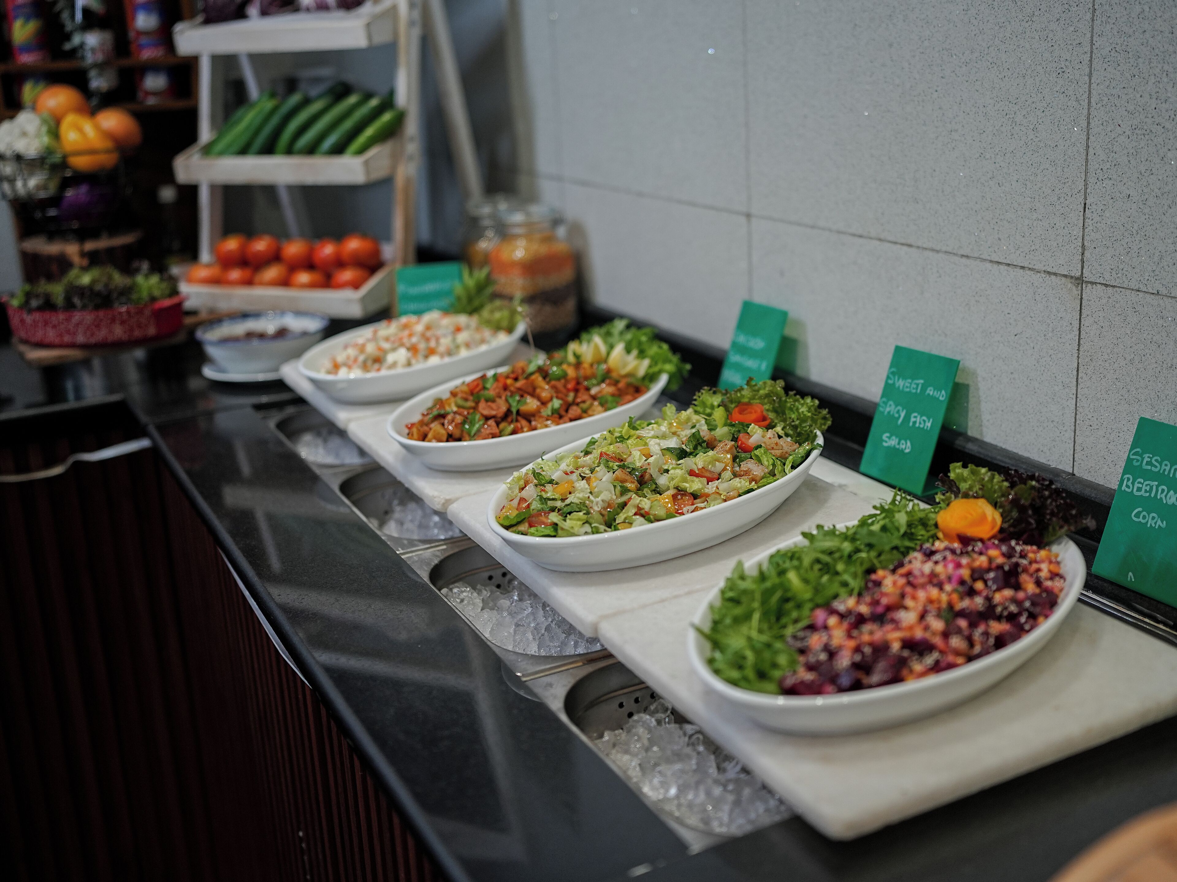 A buffet with various salads and vegetables displayed on trays.