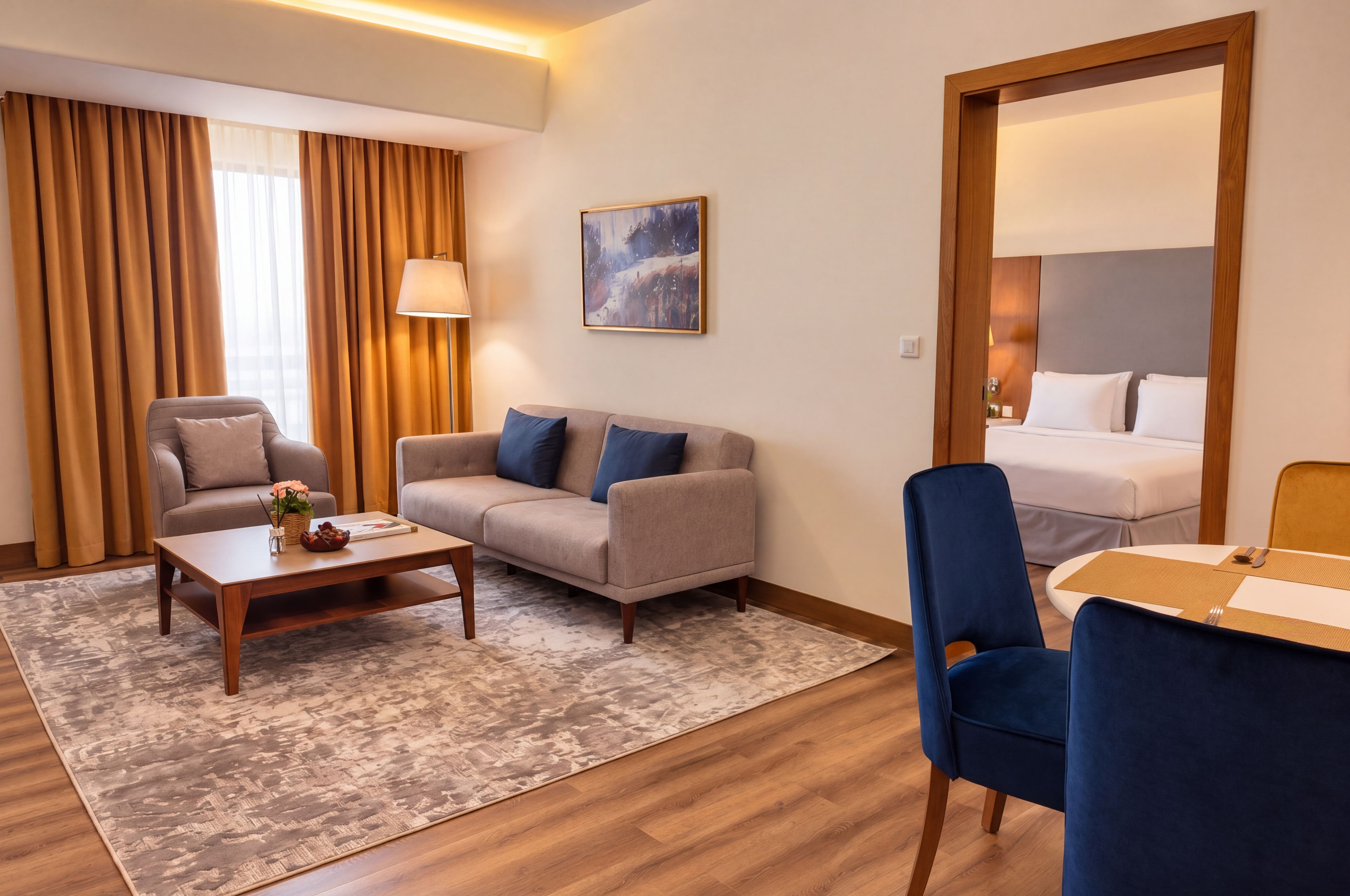 Een hotelkamer met een bank, fauteuil, salontafel en een bed.