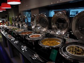 A buffet with various dishes in covered bowls, utensils, and a sign indicating 'Quiche'.