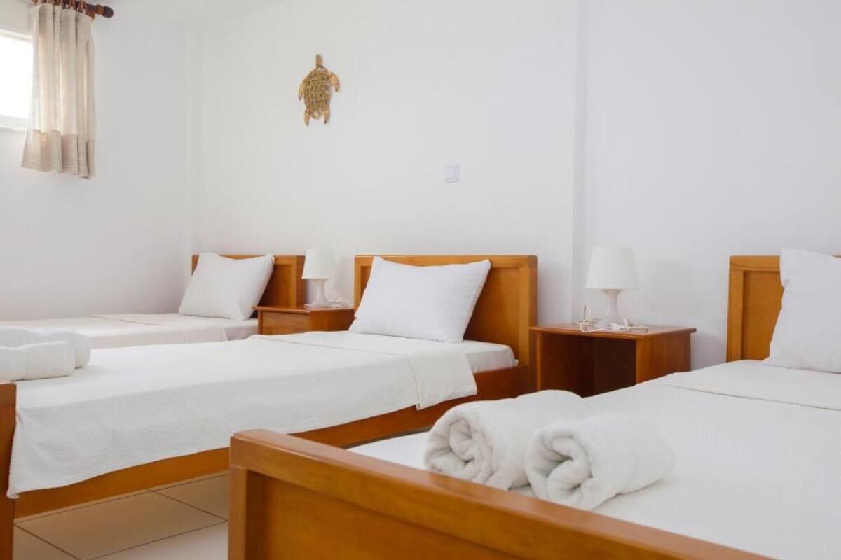 A hotel room with two single beds, each with a wooden headboard, white bedding, and a bedside lamp.