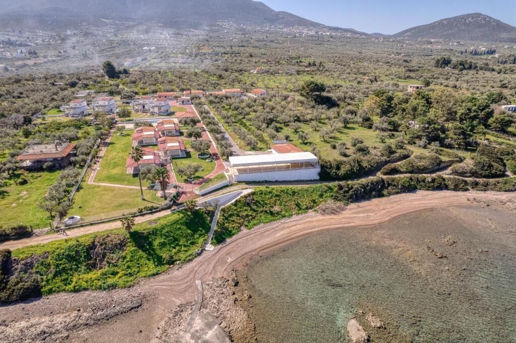 An aerial view of a coastal property with multiple buildings, a large white structure, and a beach area.