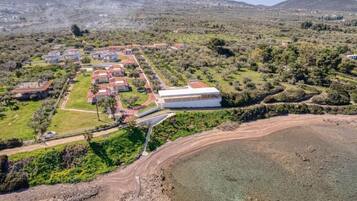 An aerial view of a coastal property with multiple buildings, a large white structure, and a beach area.