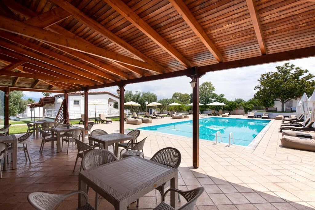 Ein Außenbereich mit Liegeplätzen, einem Pool und Tischen.