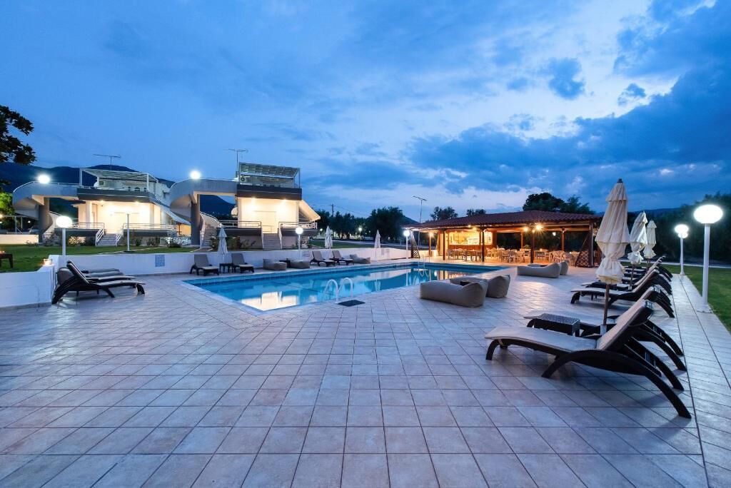 Un área de piscina con sillones de descanso y una zona de estar cubierta.