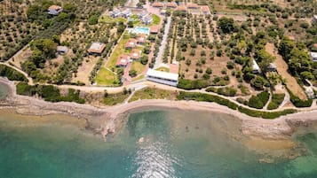 An aerial view of a coastal resort with multiple villas, a central building, and a beach.