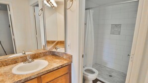 A bathroom with a sink, mirror, and shower area. - Catalina Foothills Condo on the Golf Course (Tucson)