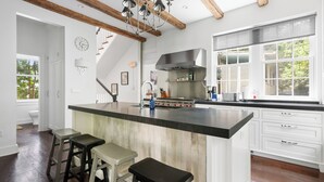 Une cuisine moderne dotée d’un grand îlot central, de meubles blancs et d’un plafond en bois.