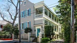 Une maison à deux étages avec un balcon, une porte d’entrée et un petit jardin devant.