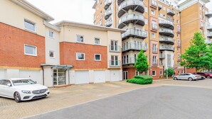 A multi-story residential building with balconies, a gated driveway, and parked cars. - Modern 2-Bedroom Apartment in Central Basingstoke  walk to Festival Place & The Avil Theatre . (Basingstoke)