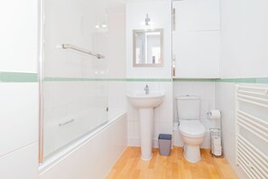 Ein Badezimmer mit Duschkabine aus Glas, einem Standwaschbecken, einer Toilette und einem Spiegel über dem Waschbecken.
