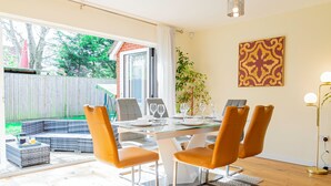 A dining area with a glass table, four orange chairs, and a view of the backyard through a sliding glass door. - 4-Bed Haven in Fawley – Ideal for extended stays, work trips, or family getaways. Spacious, fully furnished, and well-equipped for comfort and convenience. Your perfect home away from home. (Totton)