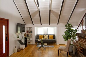 A modern living room with a sofa, a glass coffee table, a bookshelf, and a fireplace. - Dreamy Farmhouse In Studio City (North Hollywood)
