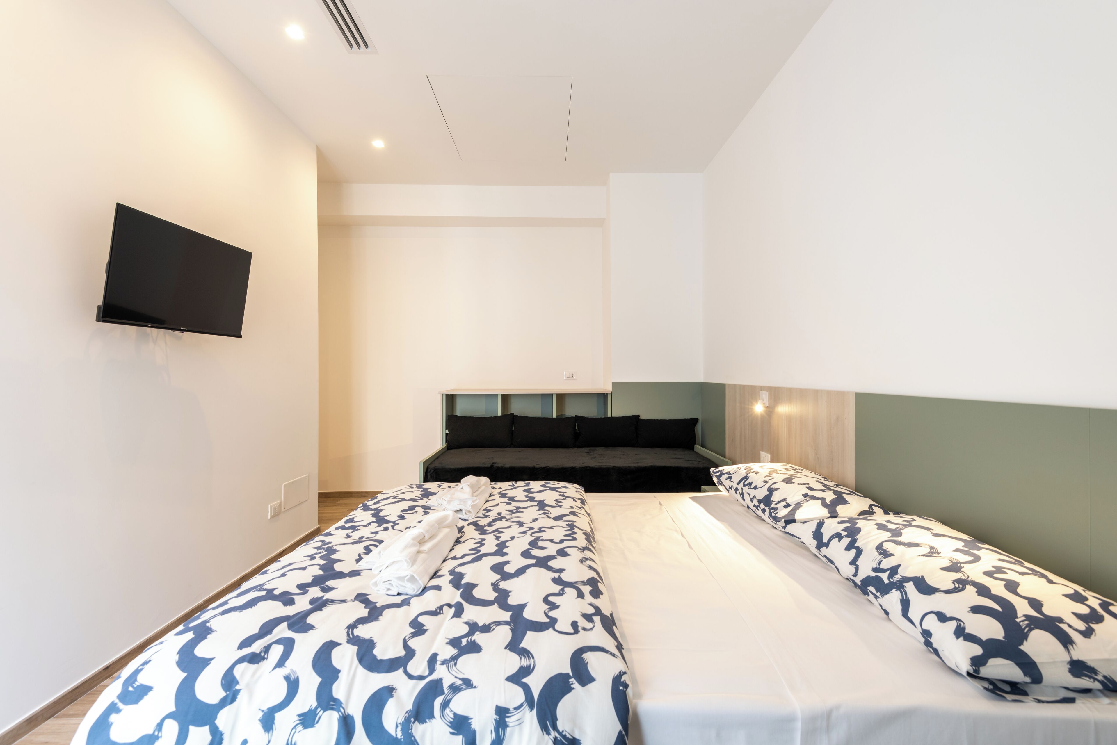 Une chambre d’hôtel avec deux lits, un téléviseur à écran plat fixé au mur et une grande fenêtre.