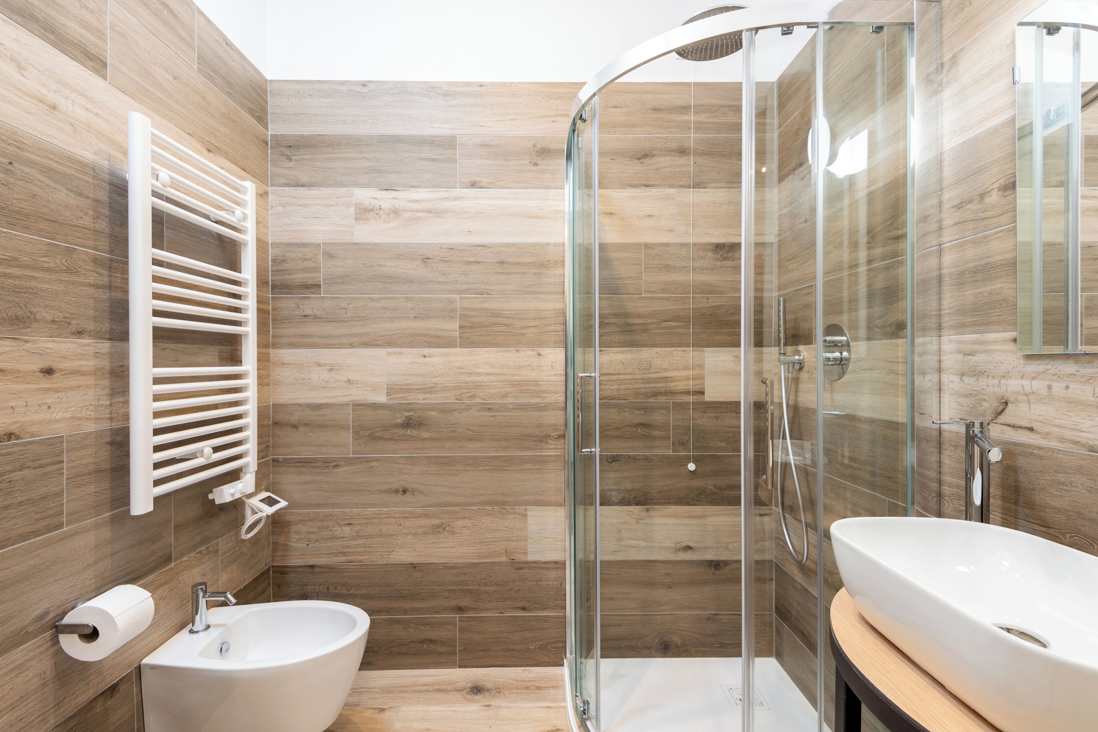 Ein modernes Badezimmer mit einer Glaskabinedusche, einem weißen Waschbecken und einem Handtuchhalter.