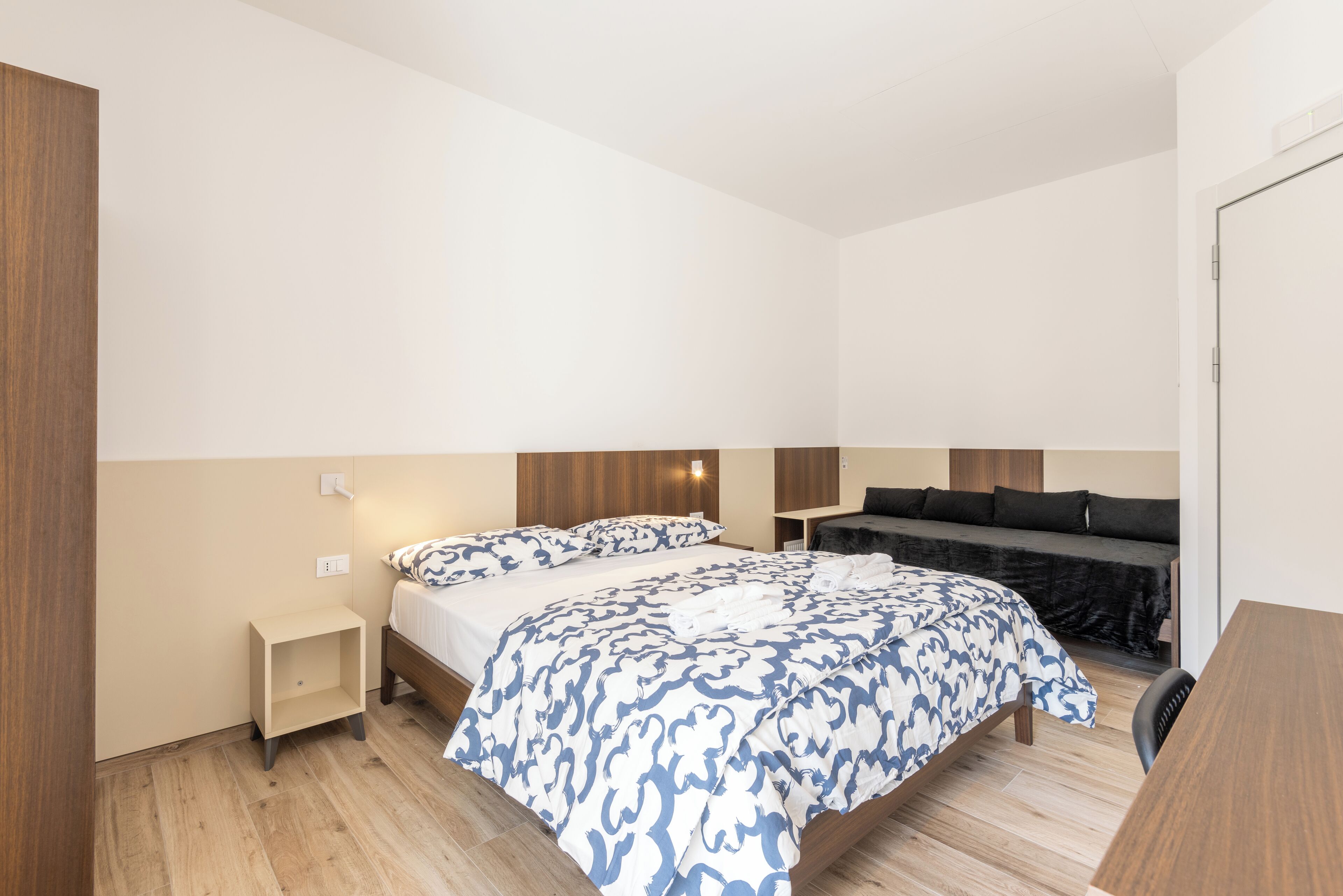 A bedroom with a bed, bedside tables, a sofa, and a desk.