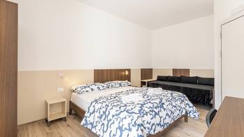 A bedroom with a bed, bedside tables, a sofa, and a desk.