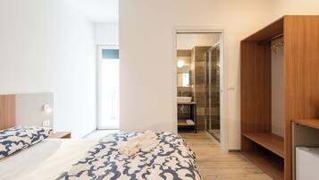 Een moderne hotelkamer met een groot bed, een houten garderobe en een badkamer die door een open deur zichtbaar is.