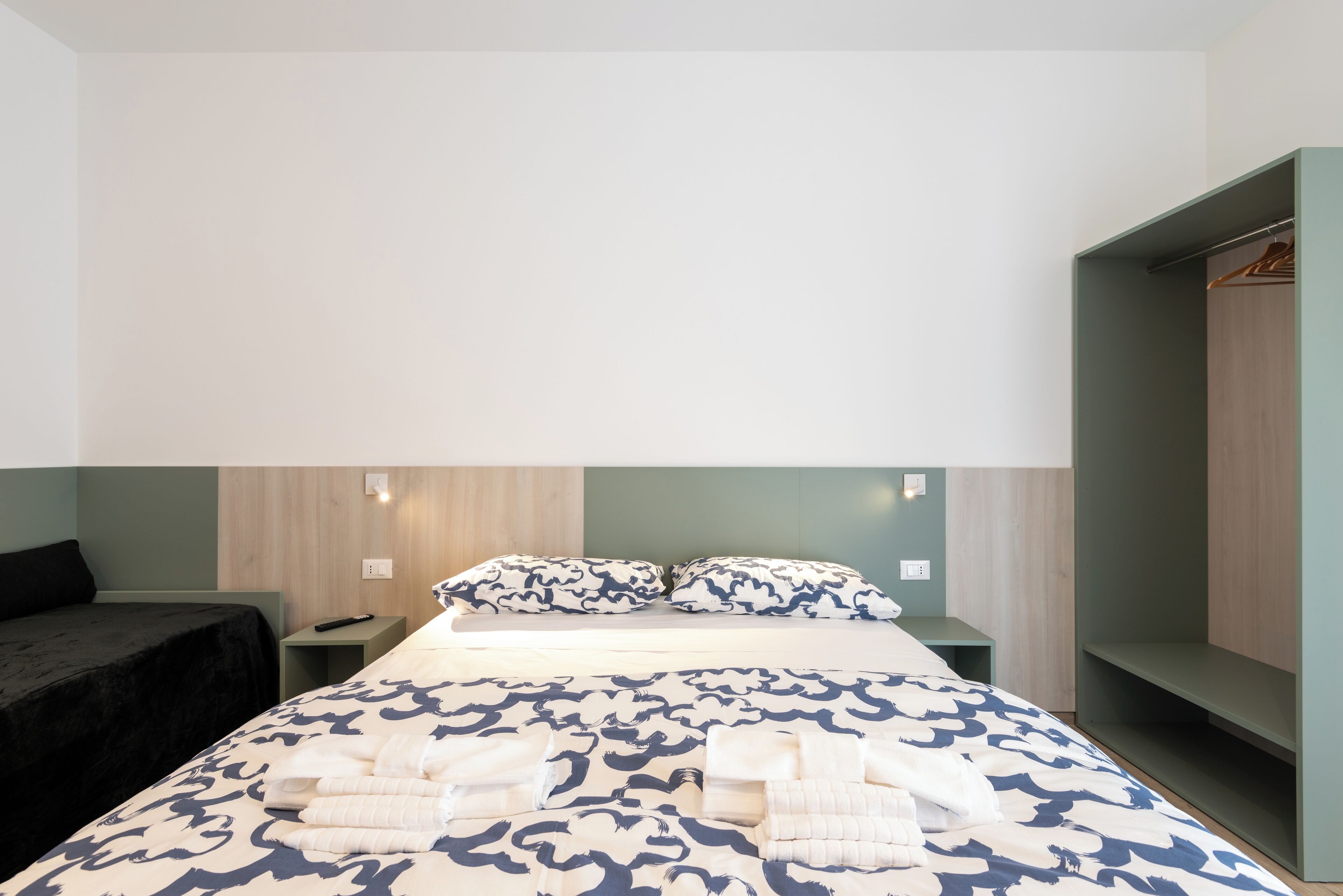A hotel room with a bed, bedside tables, a wardrobe, and a nightstand.